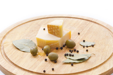 Cheese, olives, pepper and laurel leaf on a wooden board