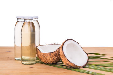 Three cold pressed extra virgin coconut oil in bottles with coconuts