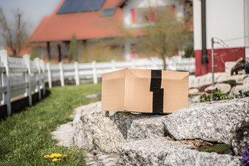 Postbote legt Paket / Schachtel im Garten des Nachbarn ab