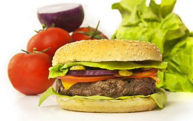 Burger with thick meat patty, with blurred vegetables in background