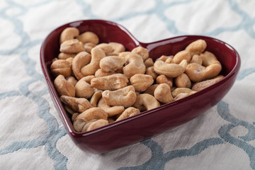 Heart shaped bowl with cashews on blue and white place mat
