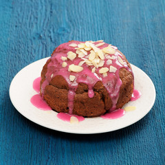 Homemade chocolate cake with violet sugar icing and almonds on b