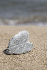 Fototapeta na wymiar naturally heart shaped stone on sand