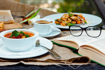 Business lunch with soup, salad and coffee served at the table in the restaurant. On the cloth lay the glasses and the book