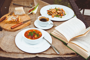 Business lunch with soup, salad and coffee served at the table in the restaurant. On the cloth lay the glasses and the book