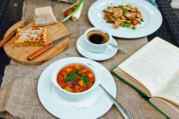 Business lunch with soup, salad and coffee served at the table in the restaurant. On the cloth lay the glasses and the book