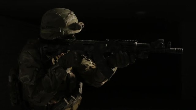 Soldier in camouflage with a gun is moved in the darkness