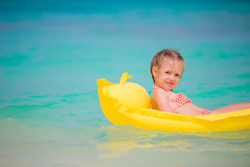 Fototapeta na wymiar Adorable little girl playing in shallow water on white beach