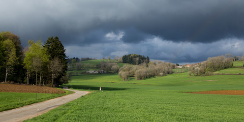 Un route à la campagne sous le soleil avec des nuages sombres menaçant