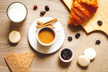 Breakfast with coffee, crackers and croissants on wooden table