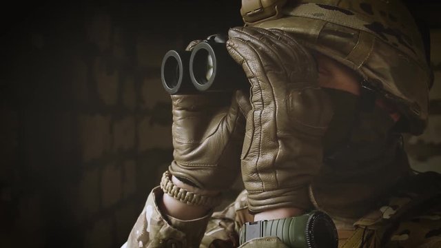 The soldier his equipment looking through binoculars. Close-up