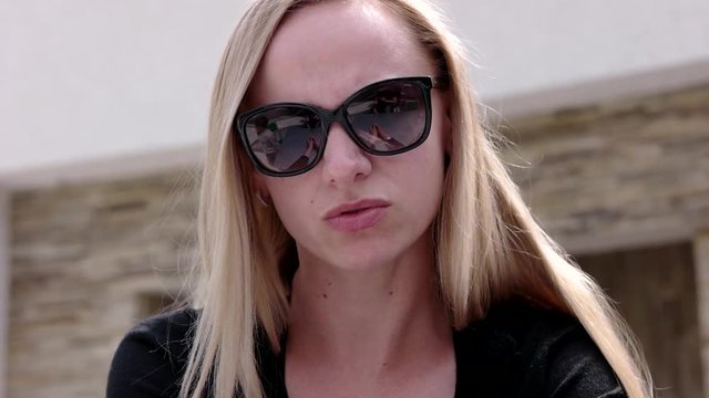 Young Business Woman in in Sunglasses at a Cafe Outdoors.