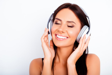 Pretty young woman listening music in headphones with closed eye