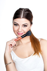 Obraz premium Beauty Girl make up artist with Makeup Brush. Bright Holiday Make-up for Brunette Woman with Brown Eyes. Beautiful Face. Makeover. Perfect Skin. Applying Makeup