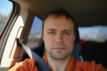 Portrait of adult man in car fastened by seat belt