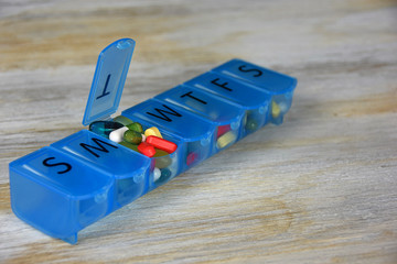 variety of pills in blue plastic pill organizer box