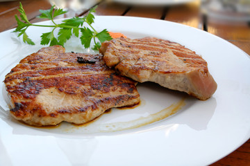Two hot, just grilled pork steaks served on the white plate.