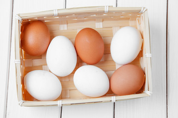 Fresh eggs in a basket on a wooden background.