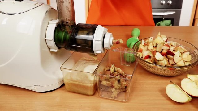 Female hands adding apple fruits in juicer machine 4K