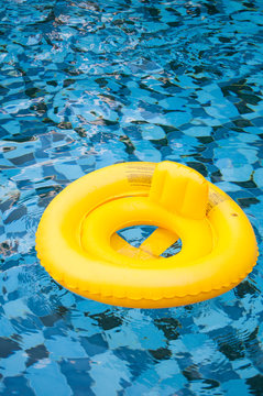 floating yellow ring on blue water swimpool with waves reflectin