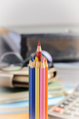 Red pencil standing out from a bunch of colored pencils