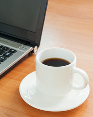 Office desk with laptop computer, and coffee cup