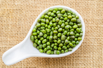 Green mung beans in white spoon.