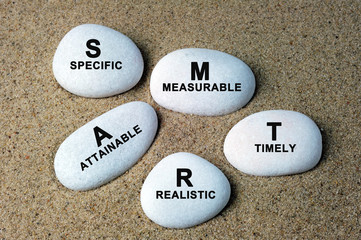 Business concept SMART goals text on a stone with sand background