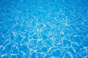 Blue and bright water with sun reflection in swimming pool