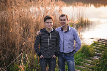 happy family father with son posing on a background of a sunset on the river