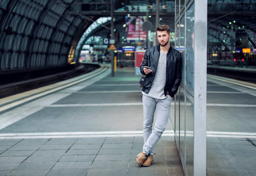 Lässiger Mann mit Smartphone am Bahnsteig