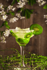 kiwi fruit soft drink cocktail with ice on a wooden background and flowers