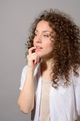 Portrait of an attractive curly young woman thinking