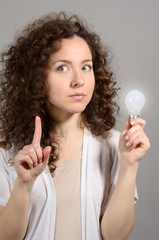 Beautiful business woman with idea light bulb on grey