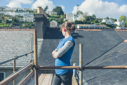 Young woman on scaffolding by roof