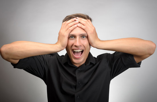 Portrait of screaming surprised man holding head