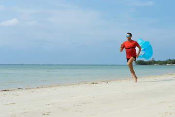The man runs, runs on the beach, in the tropical country plays sports, with attached running a parachute behind the back