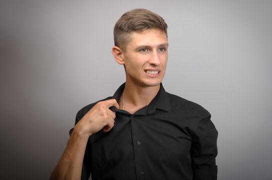 Man pull his shirt on grey background