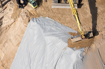 Bagger sichert Böschungsfolie