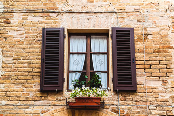 Fototapeta na wymiar Vintage window with flowers and shutters in Italy