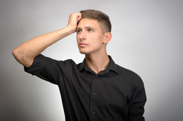 Portrait of the young thinking man with hand near face -  isolated on grey