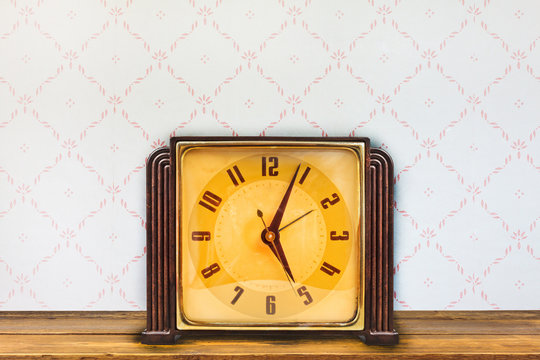 Vintage table clock in front of retro wallpaper