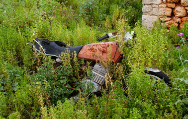 Rusty motorbike, overgrown with weed