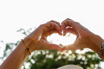 "Love sign" hand heart symbol in afternoon sun sky in vintage photo style can use for Valentine's Day season
