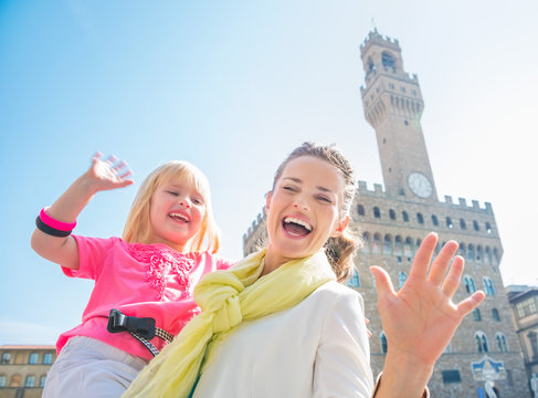 Smiling mother and daughter near Palazzo Vecchio handwaving