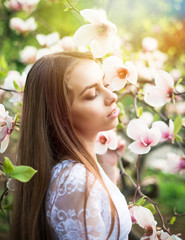 Fototapeta premium Young pretty woman enjoy in beautiful park near flowers