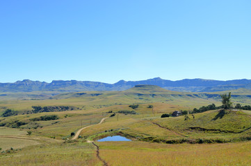 Drakensberg mountains with grass and trails and blue sky