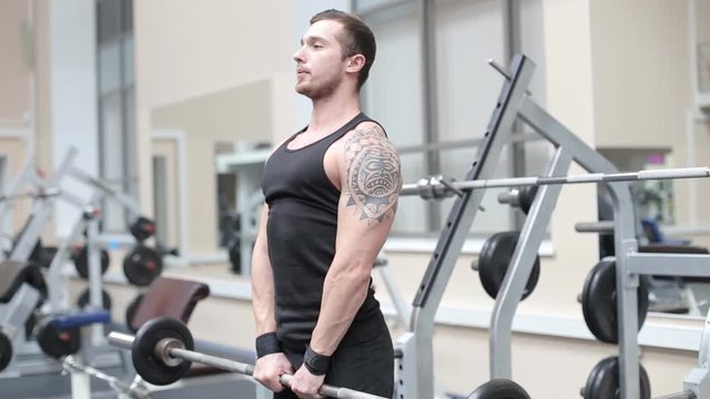 Young strong man hard train muscles in gym