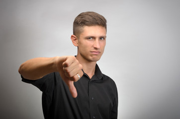 young man showing thumbs down on a gray background
