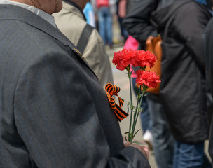 Carnation flowers in a hand of unidentified veteran. Selective focus.